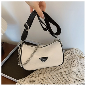 Close-up of cream pillow bag with black trim and a wide woven logo shoulder strap