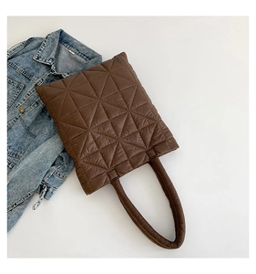 Detail of dark brown quilted puffer tote bag with triangle stitching and padded handles