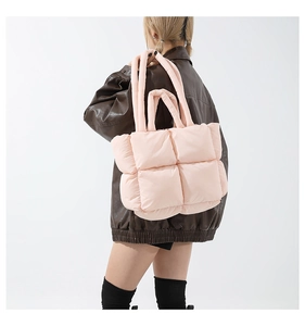 Detail view of pink quilted puffer tote bag worn over shoulder with soft down filling