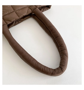 Detail shot of brown quilted tote bag showing plush texture and precision stitching