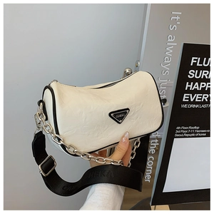 Close-up of a white leather pillow bag featuring black trim and a wide fabric strap