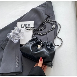 Detail of black cloud bucket bag with silver chain strap and pearl charm accent