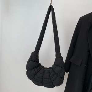 Minimalist black quilted dumpling bag with cloud-like pleats and wide shoulder strap