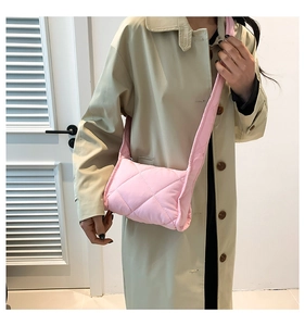 Detail van roze gewatteerde puffer crossbodytas met zachte textuur en brede schouderriem