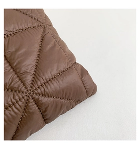 Macro detail of high-quality triangular quilting on a brown glossy puffer tote bag