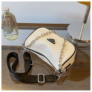 Detailed macro view of the cream pillow bag with black wide strap and silver chain details