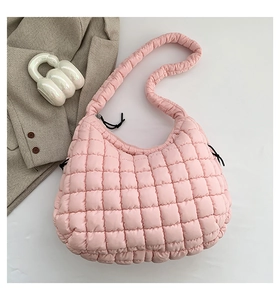Detail of light pink quilted puff shoulder bag with soft padded texture and strap