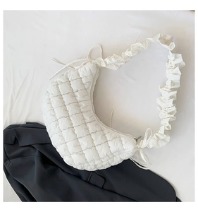 Flat lay of white quilted dumpling bag with ruffled straps and textured plaid finish