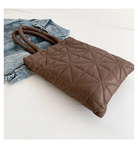 Macro detail of brown quilted down tote bag featuring geometric triangular stitching