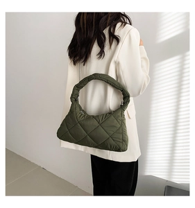 Modèle portant un sac matelassé vert foncé avec surpiqûres en losange et zip argenté