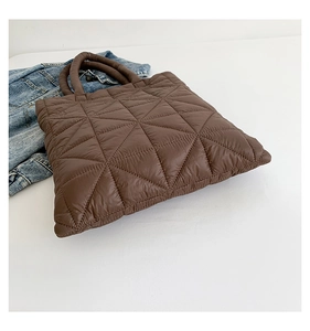 Macro shot of brown quilted tote bag with puffy down fabric and cylindrical handle
