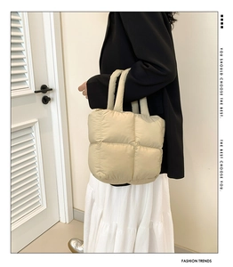 Detail of beige quilted puffer tote bag with soft down cotton texture and large compartments