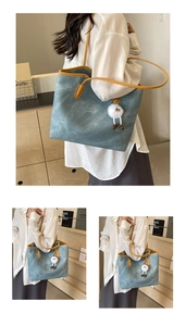 Detail of teal tote bag with yellow straps and white plush pendant for daily commute