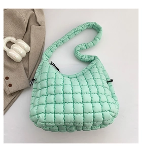 Macro shot of mint green quilted cloud bag with soft puffy texture and padded handle