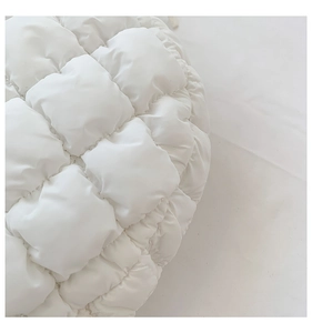 Macro detail of white quilted dumpling bag with soft bubble texture and woven fabric