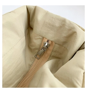 Makroaufnahme von Reißverschluss und gestepptem Nylongewebe einer beige Umhängetasche
