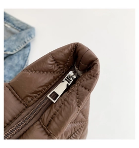 Detail of a brown quilted bag featuring nylon fabric and a silver metal zipper