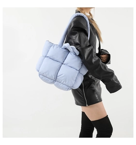 Close-up of light blue quilted down cotton tote bag with soft padded shoulder strap