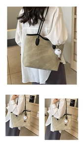 Detail of olive green tote bag with black piping and cute white plush ball pendant