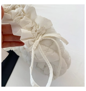 Detailed close-up of white quilted dumpling bag featuring pleated ruffle edges and drawstring