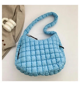Top view of light blue quilted cloud bag with puffy square patterns and wide shoulder strap