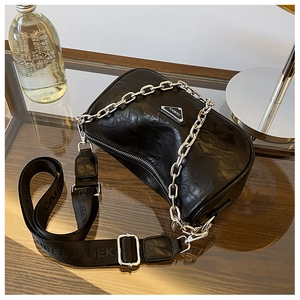 Macro shot of black pleated leather crossbody bag with silver chain and metal logo detail