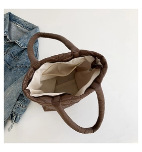 Detail shot of a brown quilted tote bag showing its spacious interior and zipped pocket