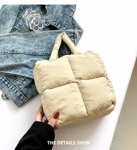 Detail of beige quilted puffer tote bag featuring oversized grid stitching and padded handles