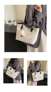 Close-up of beige marble-textured tote bag with black straps and plush doll charm