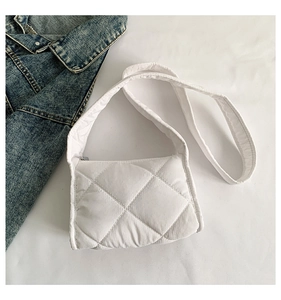 Detail van witte gewatteerde puffer schoudertas met ruitstiksels en een brede schouderband