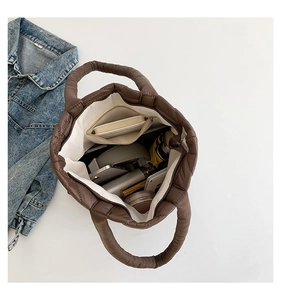 Spacious brown quilted tote bag showing large internal capacity with various daily items