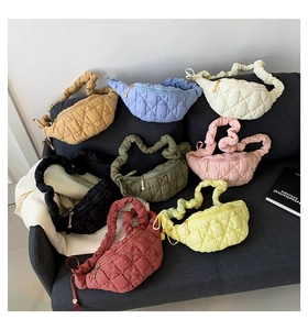 Detail showing various colors of quilted cloud bags with pleated straps on a sofa