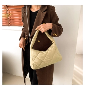 Sac à bandoulière matelassé beige porté avec un élégant manteau d'hiver en laine marron