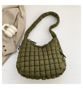 Detailed macro view of olive green quilted bubble fabric and zipper closure on shoulder bag