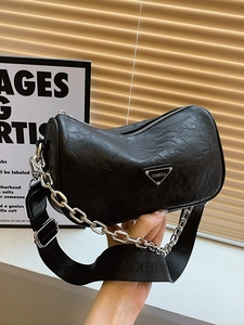 Minimalist black pillow bag with wide shoulder strap and chunky silver chain detail