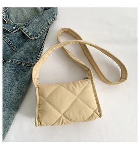 Detailopname van beige gewatteerde nylon schoudertas op een blauwe denim achtergrond