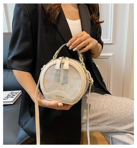 Detail of round beige crossbody bag featuring floral embroidery and BOWEN branding