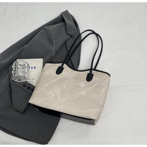 Close-up of minimalist beige tote bag with black trim and spacious interior layout
