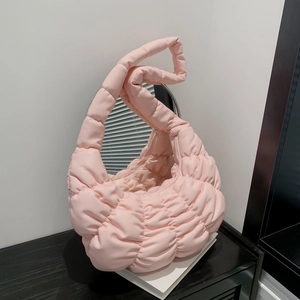 Pink pleated cloud bag with twisted handle and quilted design on white pedestal