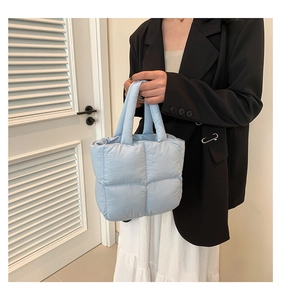 Detail view of light blue quilted down tote bag with soft padded texture and top handles