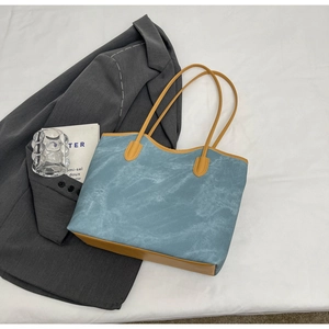 Detail of blue marble textured tote bag with bright yellow leather trim and handle