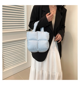 Close-up of light blue quilted puffer tote bag with soft padded handles and nylon texture