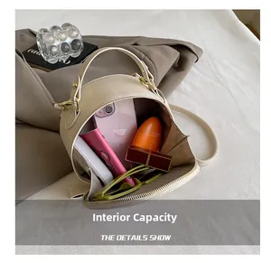 Internal view of beige circular bag showing storage for phone, wallet, and sunglasses