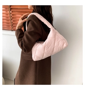 Détail du sac hobo matelassé rose avec surpiqûres en losanges sur l'épaule du mannequin