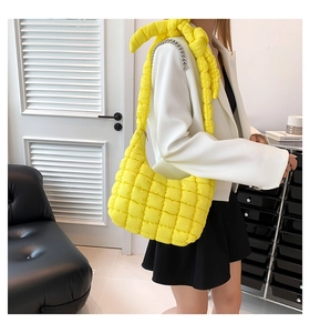 Detalle del bolso acolchado amarillo brillante con cadena plateada y nudo en la correa de hombro