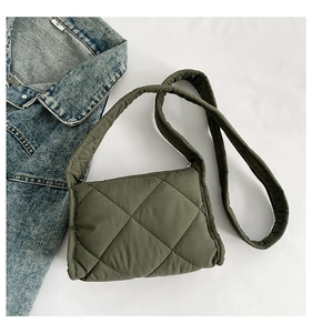 Legergroene gewatteerde schoudertas met blauw denim overhemd op een witte achtergrond