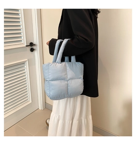 Close-up of a light blue quilted puffy tote bag with soft square padded texture and handles