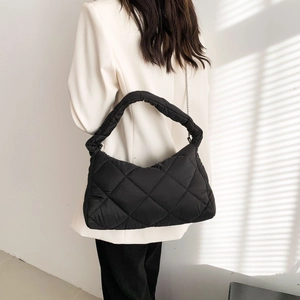 Détail d'un sac bandoulière noir matelassé avec texture chic et chaîne en métal