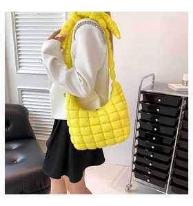 Primer plano de bolso acolchado amarillo brillante con adorno de cadena plateada