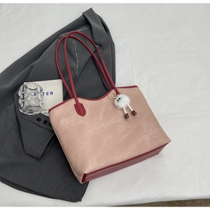 Detailed view of bicolor tote bag with pink suede texture and red handle on white fabric